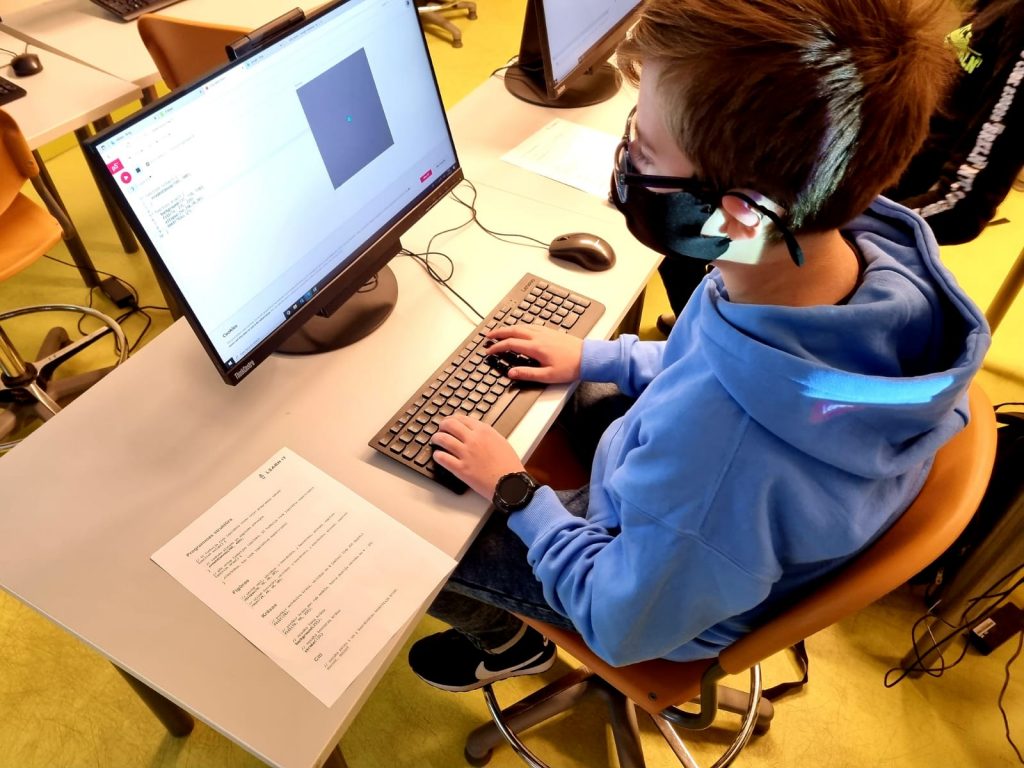 Zēns sēž pie datora un strādā uz ausīm austiņas