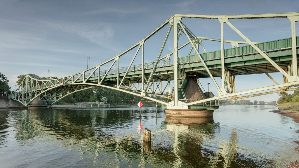 Oskara Kalpaka tilts uz mierīga ūdens un zilām debesīm