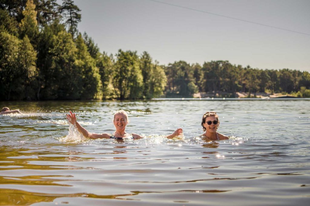 Divas sievietes smaidīgas peldas ezerā