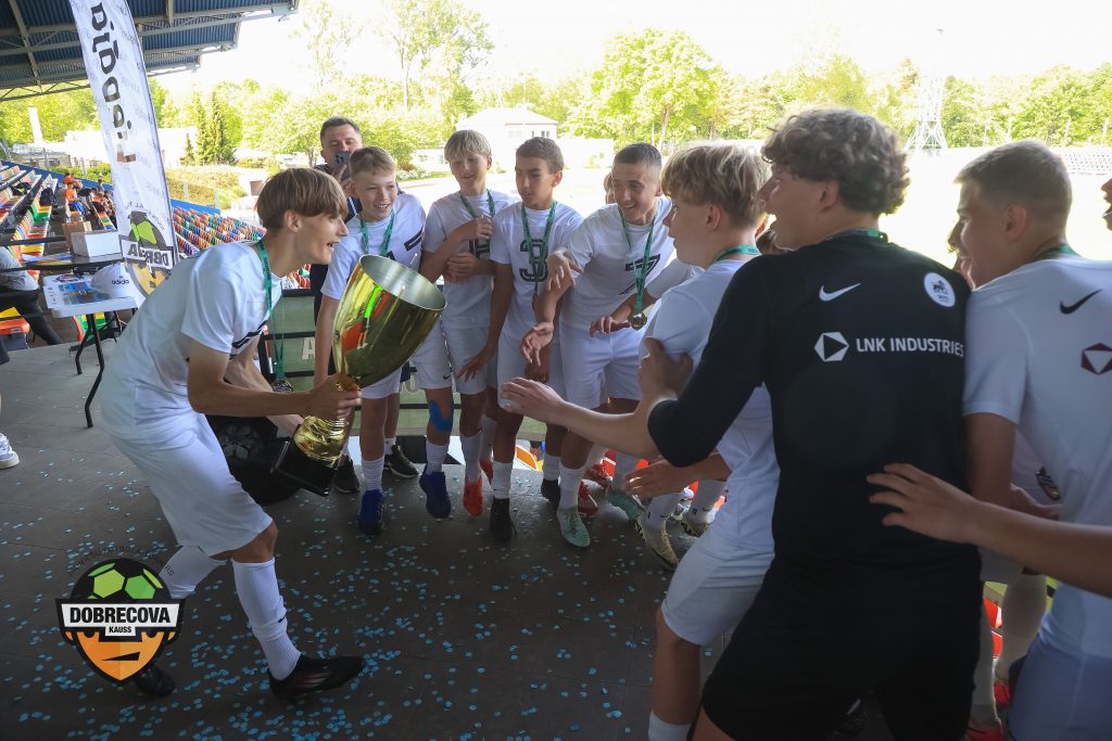 Futbolistu komanda pēc uzvaras. Futbolisti rokās tur lielo turnīra kausu