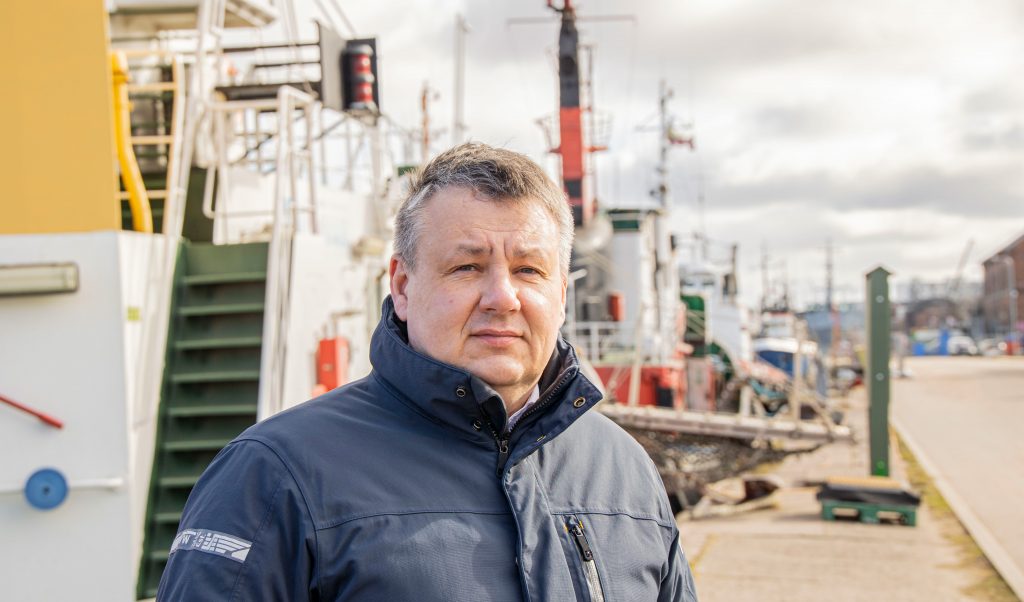 Vīrietis stāv pie kuģiem Liepājas ostā